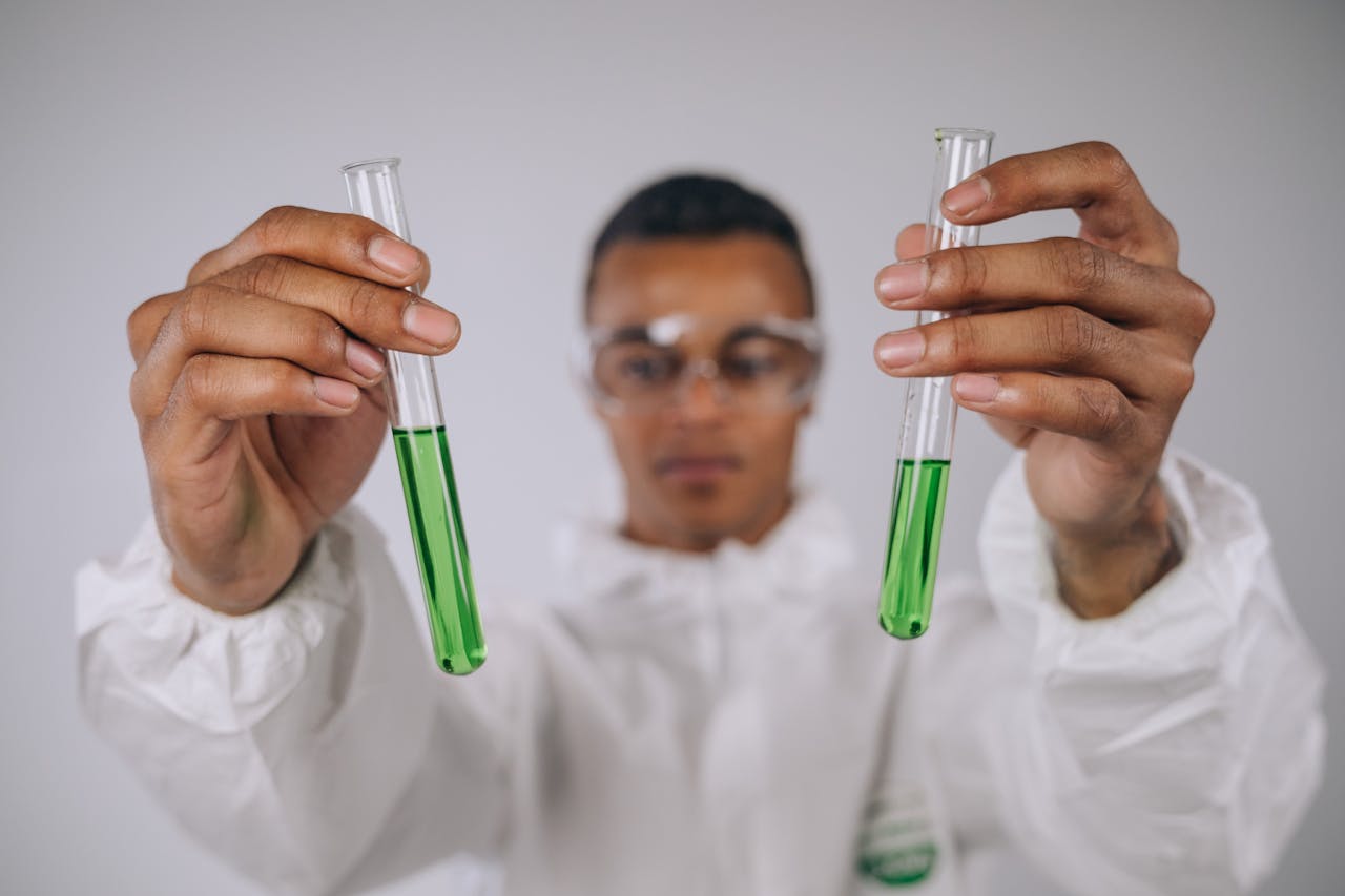 Focused scientist examining green liquid in test tubes, conducting research